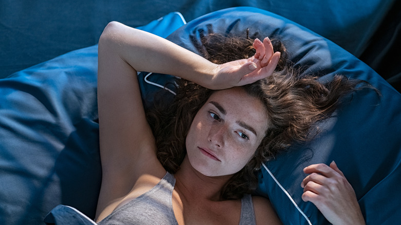 young woman lying awake in bed