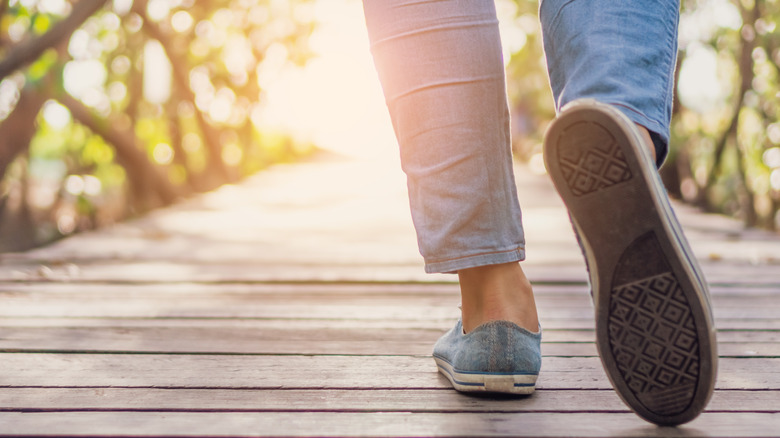 woman's feet and legs walking on bridge