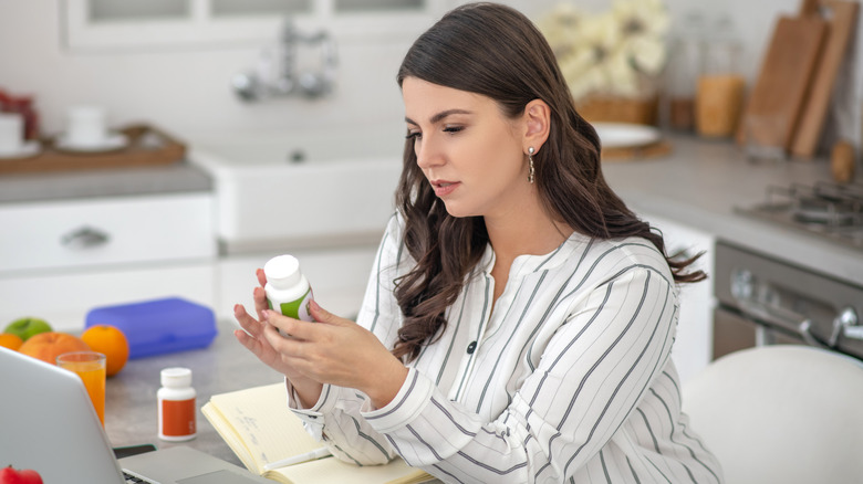 woman examining dietary supplement bottle