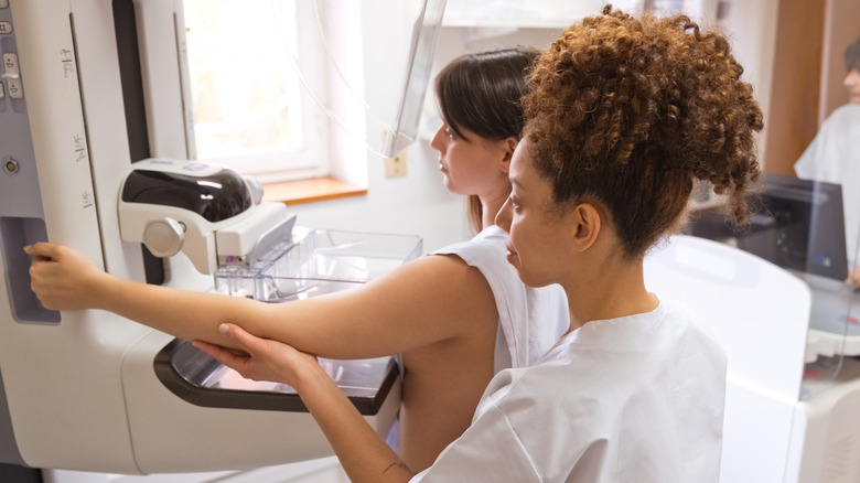 Doctor assisting woman with mammogram 