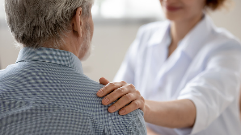 Doctor comforting older man