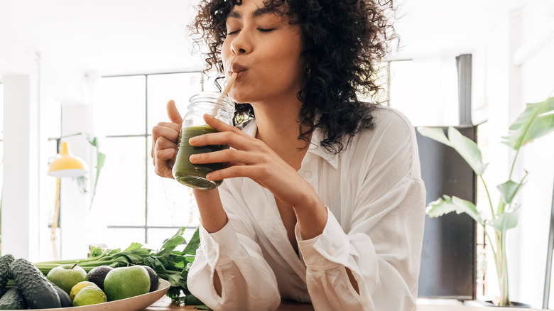 woman drinking green fruit smoothie