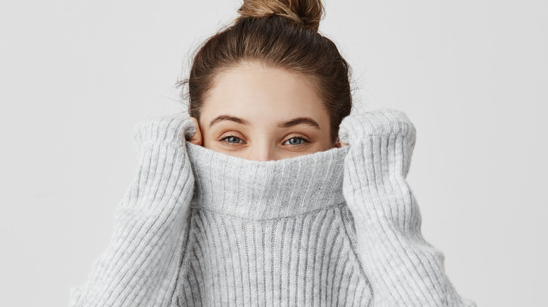 woman hiding under oversized sweater