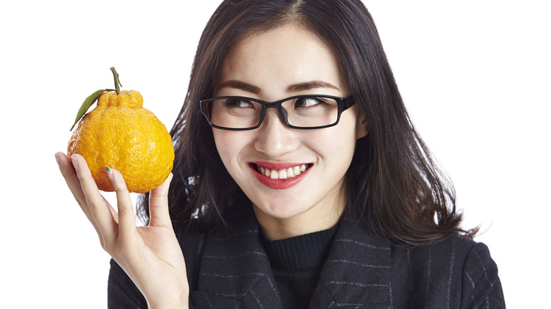 happy young woman holding an ugli fruit