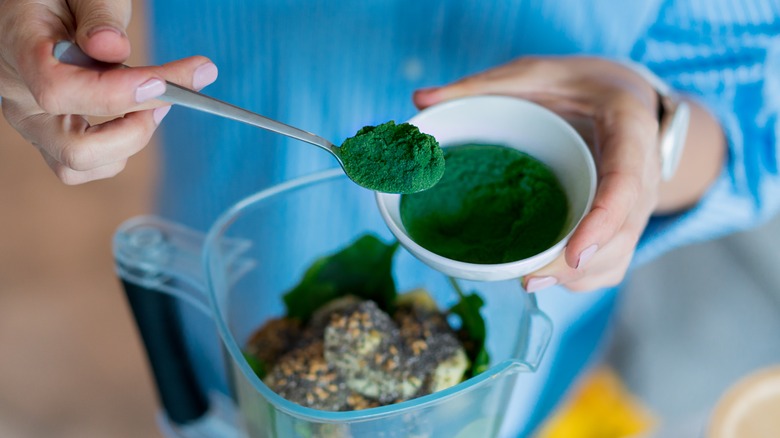 adding spirulina powder to smoothie mixture