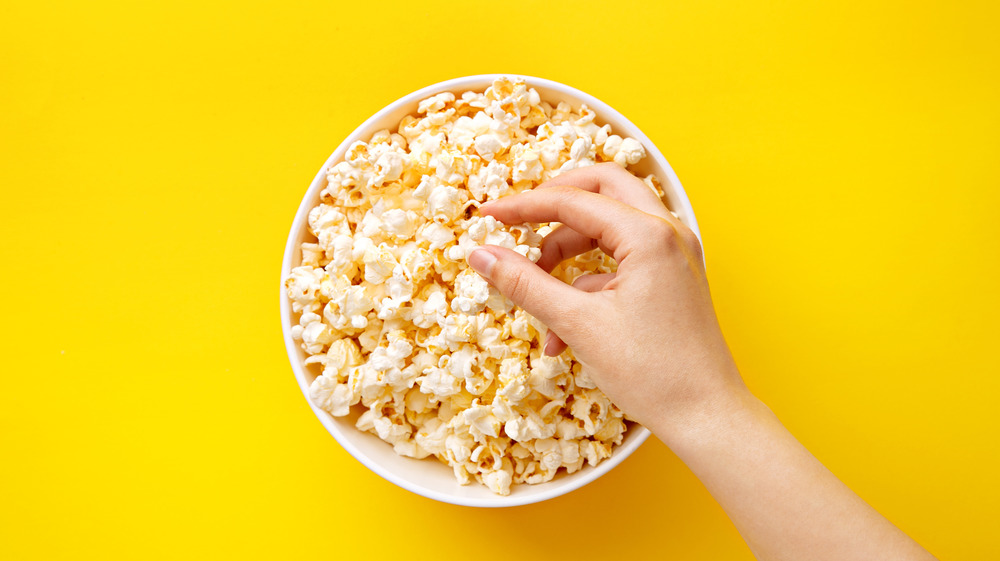 hand reaching in popcorn bowl