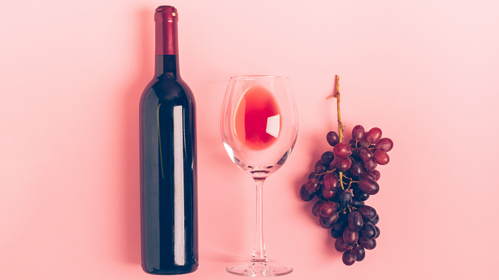 bottle of red wine, glass, and grapes