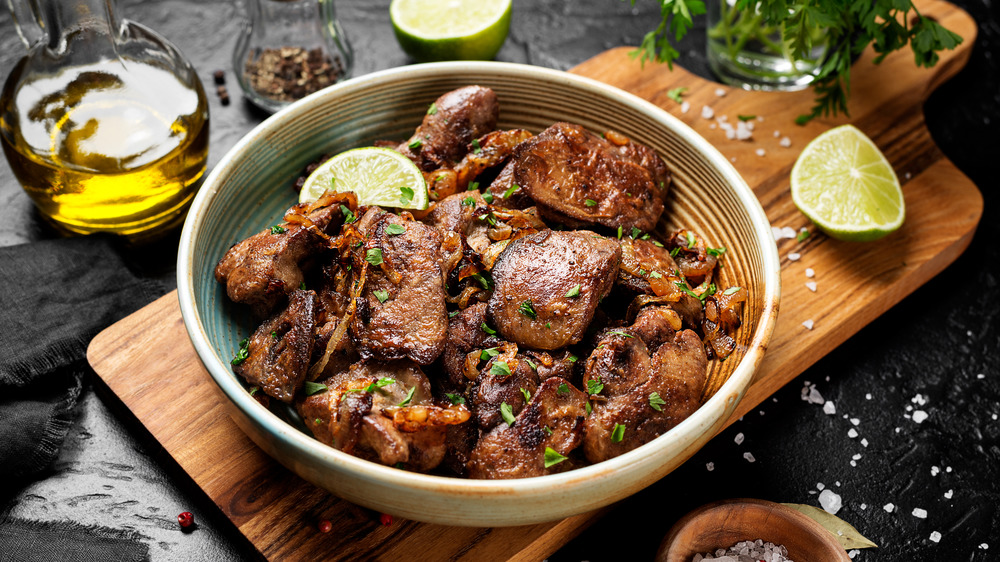 Cooked chicken liver, lime wedges, and herbs