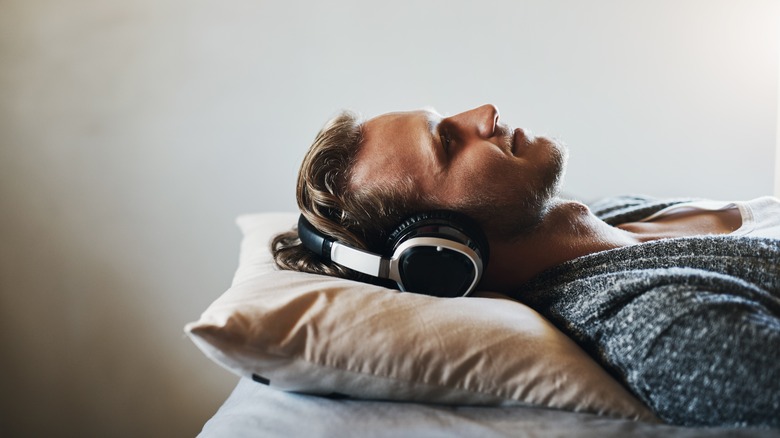 Man lying in bed listening to headphones