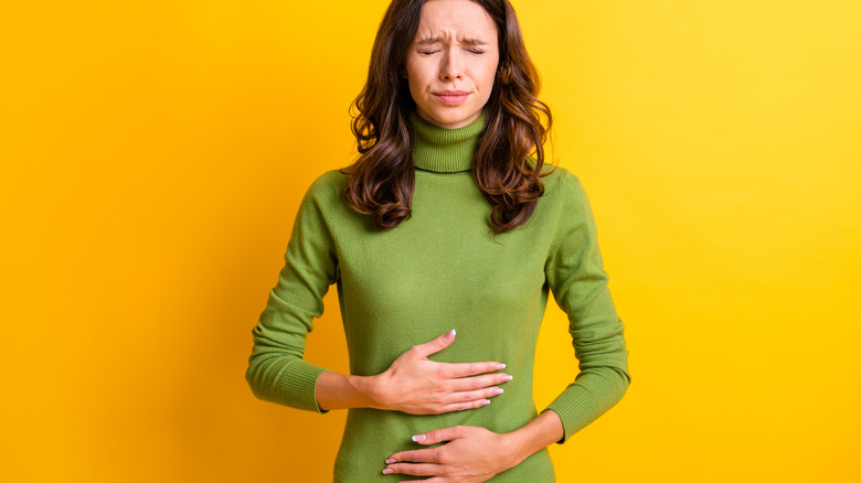 uncomfortable looking woman holding stomach