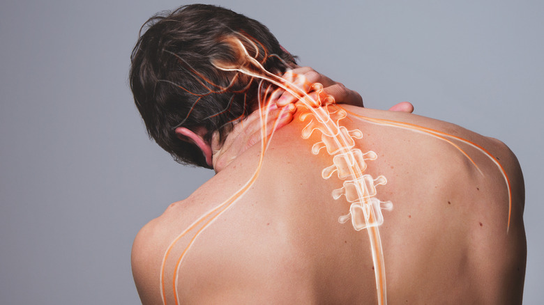 bare back man holding back of neck with pain symbol in red