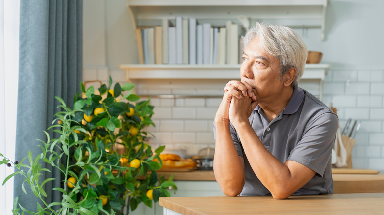 An older man sitting alone in his kitchen