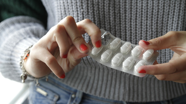 A woman's hands opening a blister pack of pills