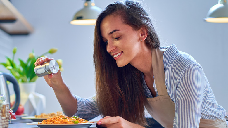 Woman sprinkling salt on her food