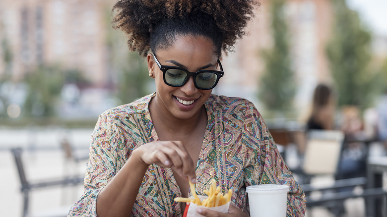 Smiling woman eating French fries