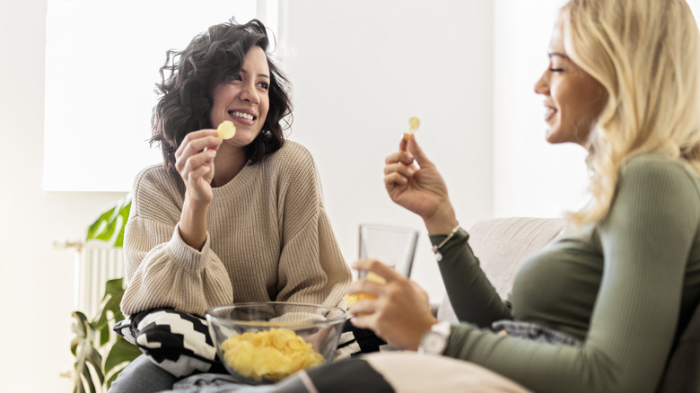 Women eating chips on the couch