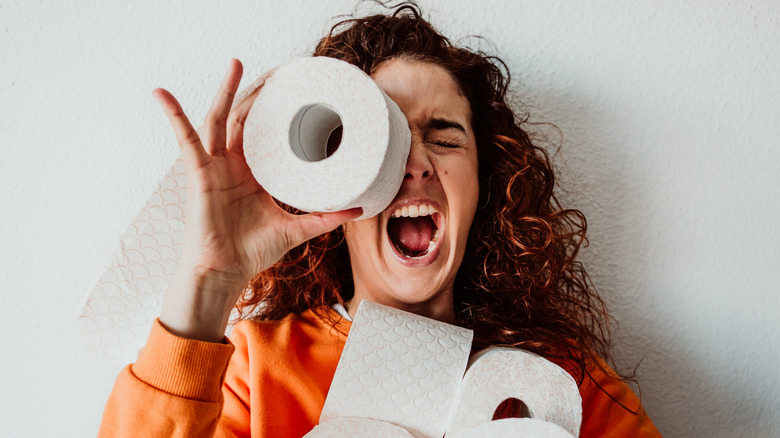 A woman holding toilet paper rolls