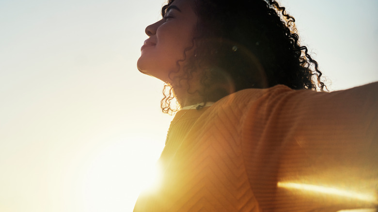 Woman with her arms spread as she basks in sunshine