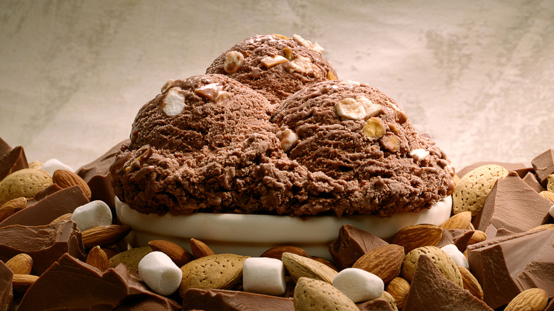 Three large scoops of ice cream atop a mound of nuts, marshmallows, and chocolate 