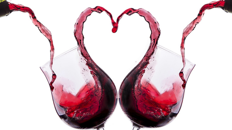 Red wine overflowing glasses forming heart