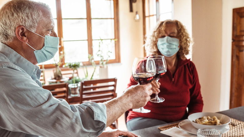 Couple wearing masks toasting red wine
