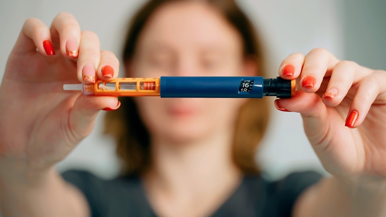 Woman holding up an insulin pen