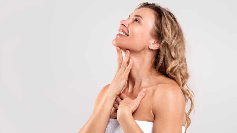 A woman smiles and touches her hand to her soft skin