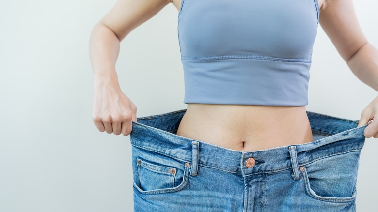 Woman holding larger sized pants as weight loss concept
