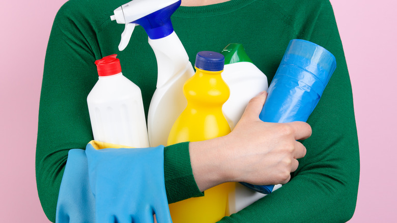 Person holding household cleaners and rubber gloves