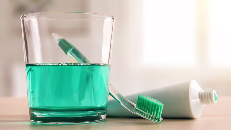 Mouthwash in a glass by toothbrush and toothpaste