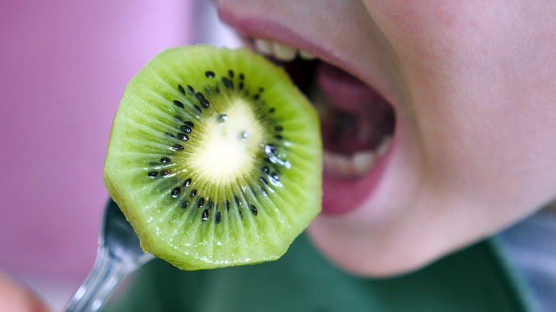 a person biting into a kiwi