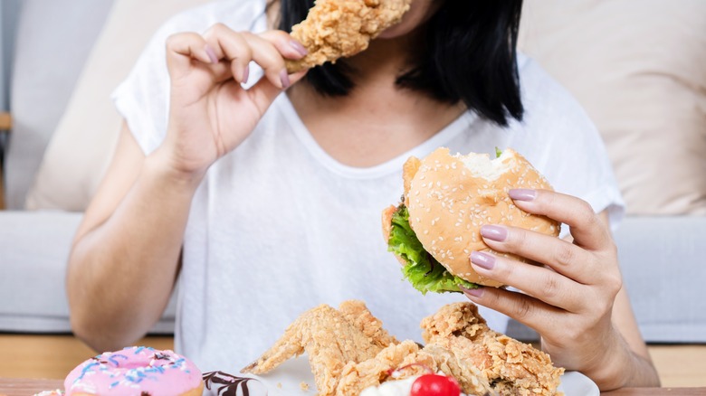 woman eating chicken and donuts
