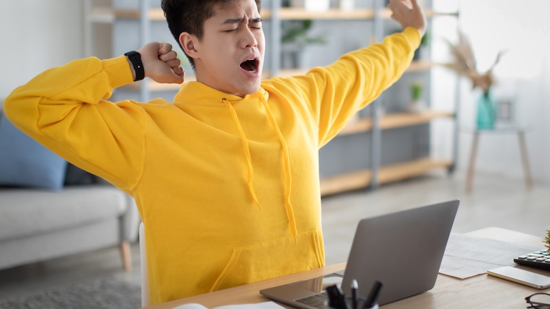 young man yawning while working