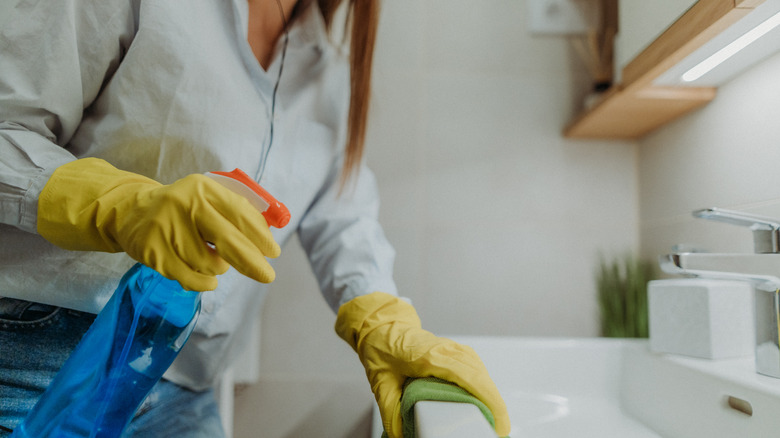 Woman cleaning her bathroom wearing yellow gloves