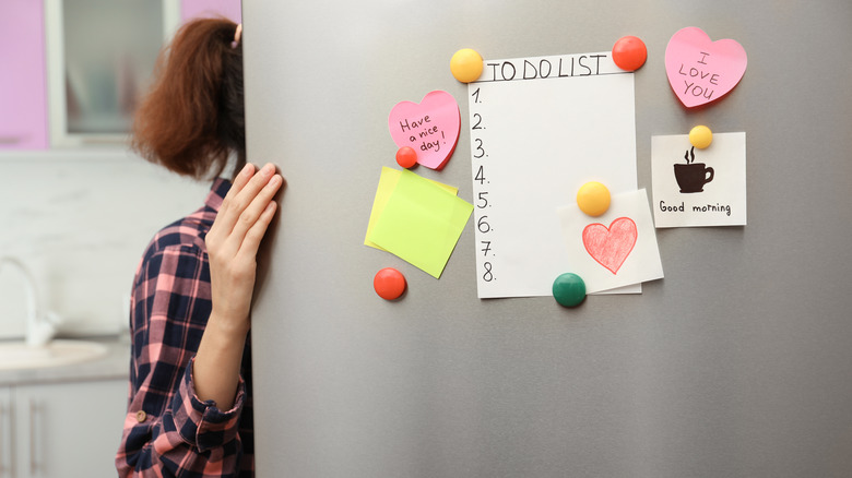 Woman opening refrigerator door with magnets