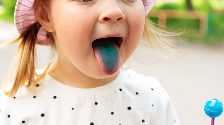 young girl sticking out blue tongue