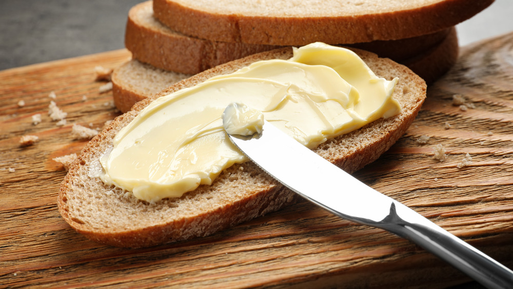 Knife spreading butter on a piece of bread