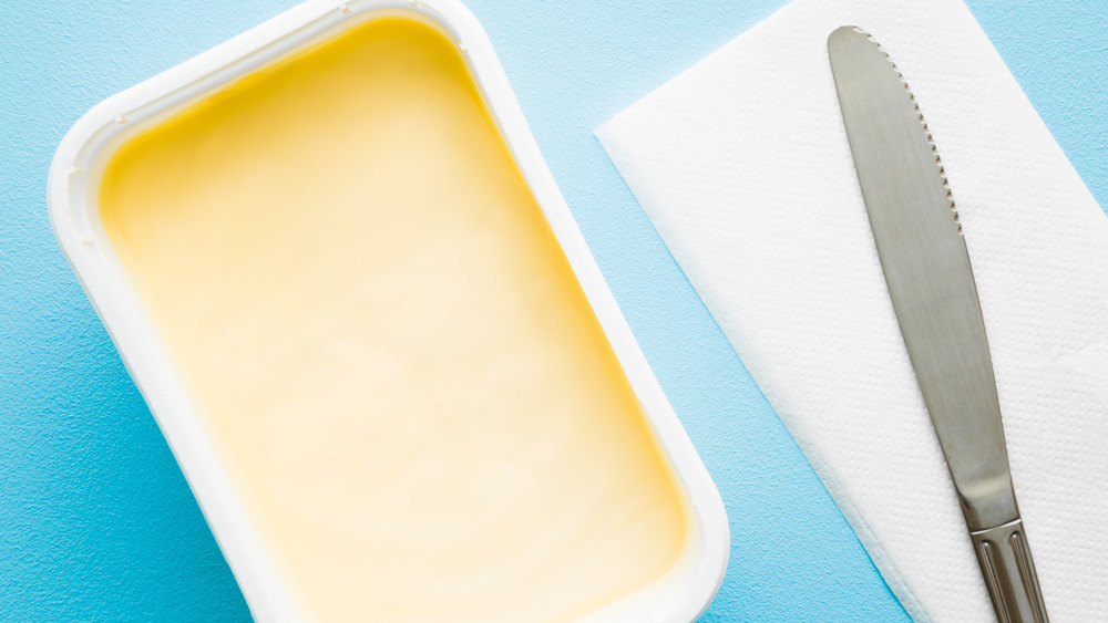 Tub of margarine next to a knife