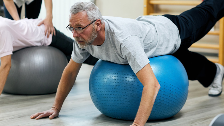 senior man lying face forward on a stability ball