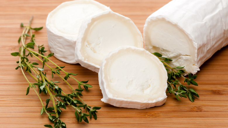 Goat cheese with thyme on wooden cutting board