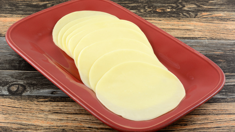 Slices of Provolone cheese on red plate