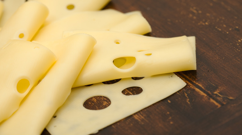 Swiss cheese slices on wooden table