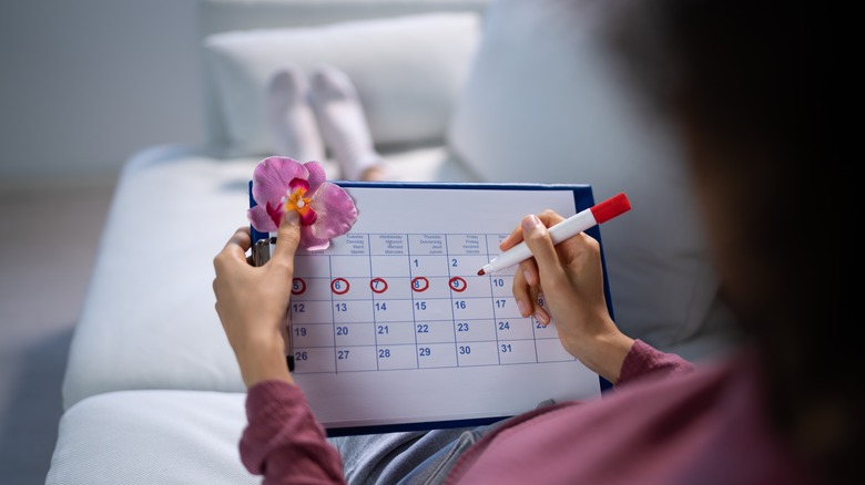 woman marking menstrual cycle on calendar