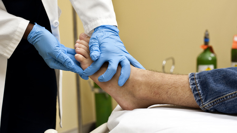 doctor's hands looking at man's foot