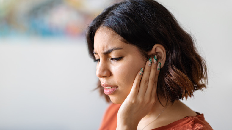 woman with concerned look holding her ears