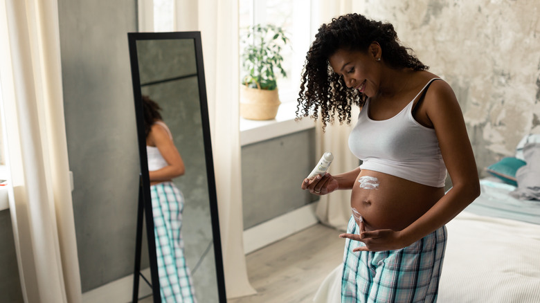 pregnant woman moisturizing skin