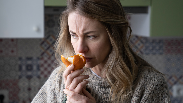 Woman trying to smell and orange