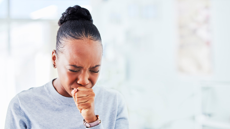 Woman coughing into her fist