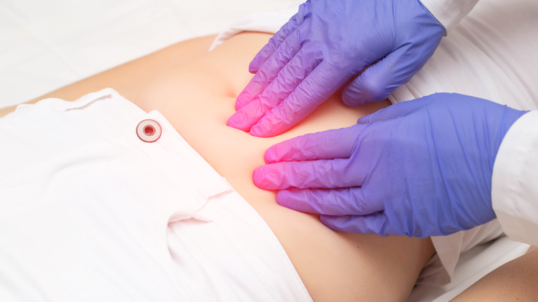 doctor examining woman's abdomen