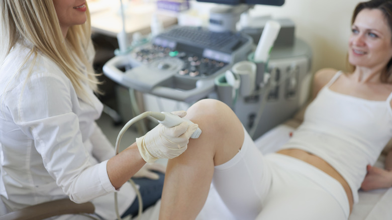 A doctor performing an ultrasound on a woman's leg